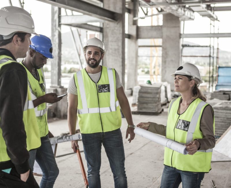 Woman in protective workwear and construction workers in construction site